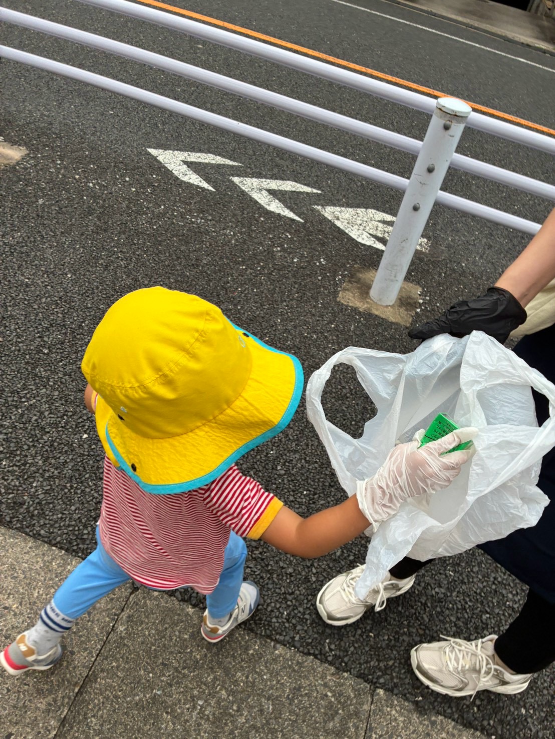 拾ったゴミを袋へ入れている子どもの手元