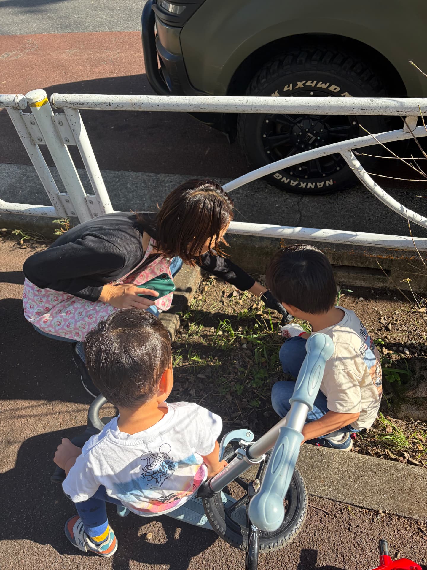 スタッフと子どもたちが植え込みのゴミを一緒に拾っている様子