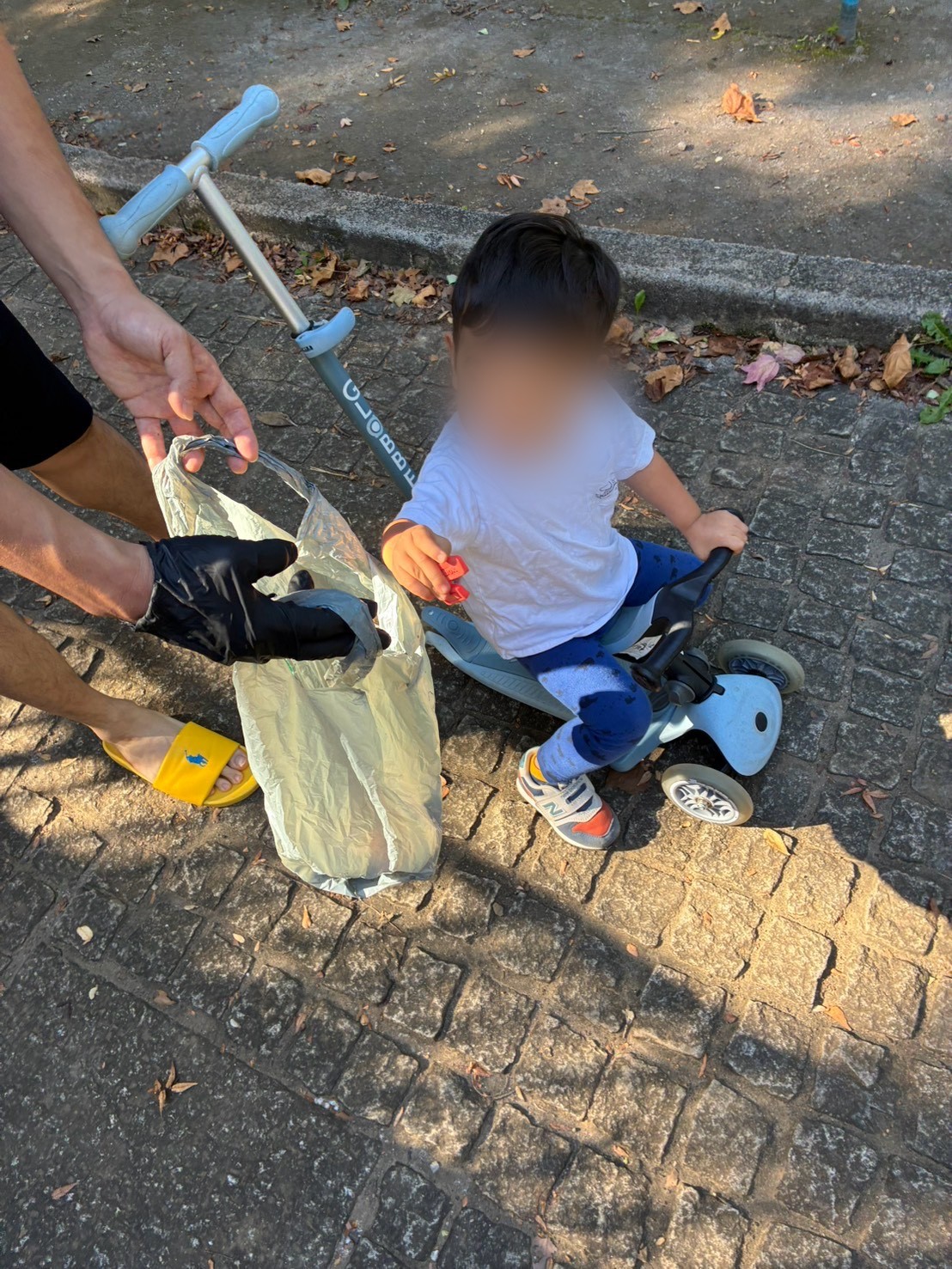 小さな子どもが拾ったゴミをゴミ袋へ入れている様子