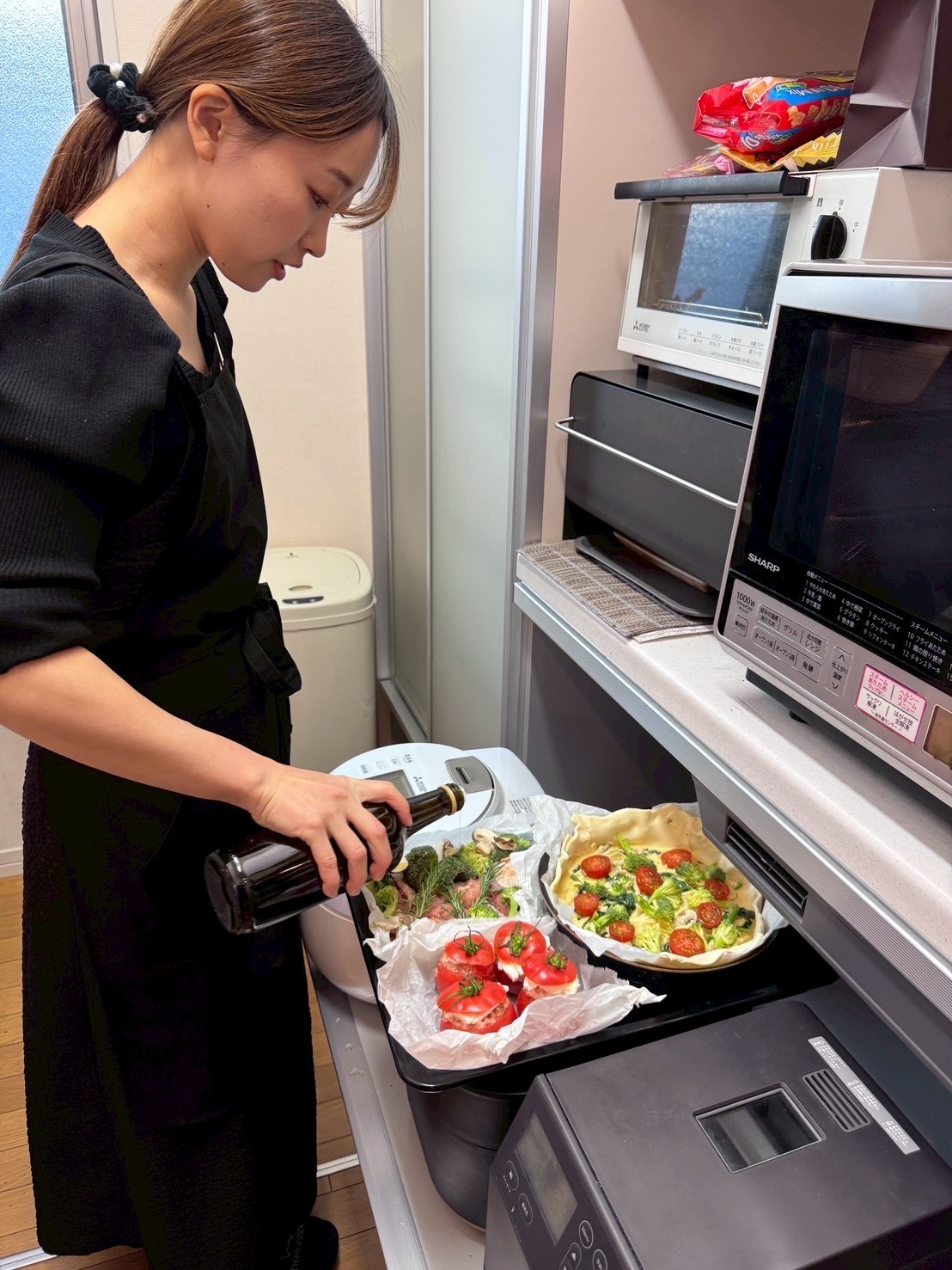 黒いエプロン姿でオーブン料理を仕上げるスタッフ
