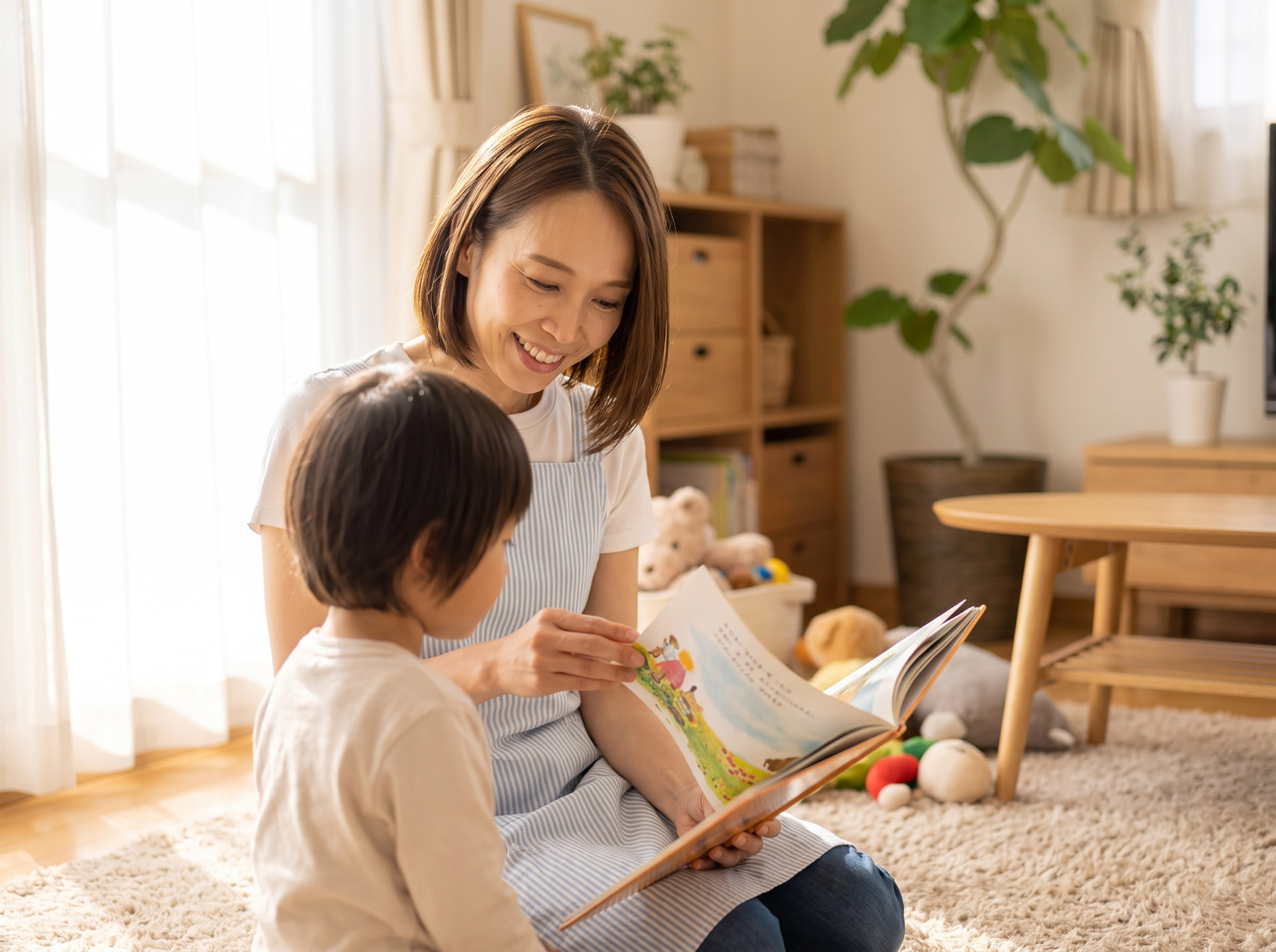 リビングでお子様と一緒に絵本を読んで笑顔で寄り添うスタッフの様子